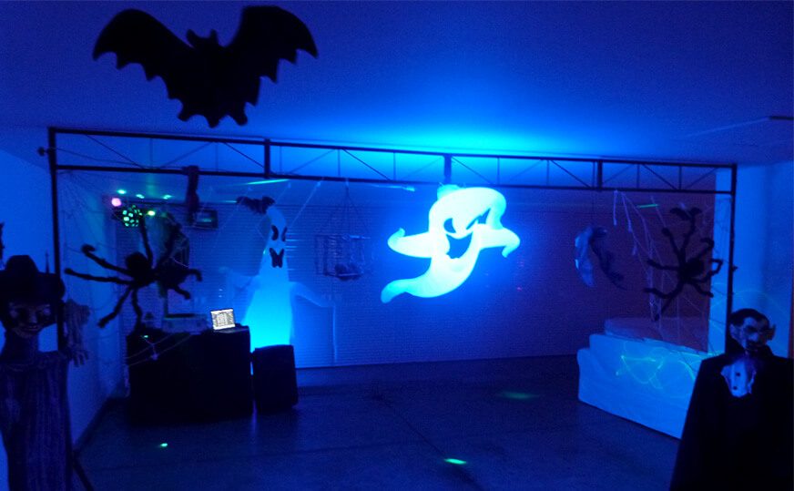 Pista escura com luz azul, morcegos e fantasma iluminado em festa de Halloween