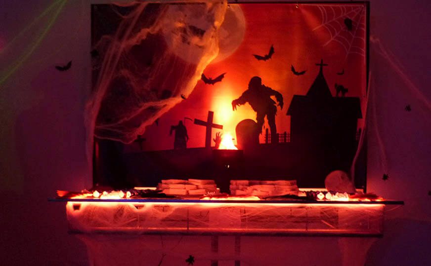 Mesa iluminada de Halloween com teias de aranha e silhuetas de cemitério