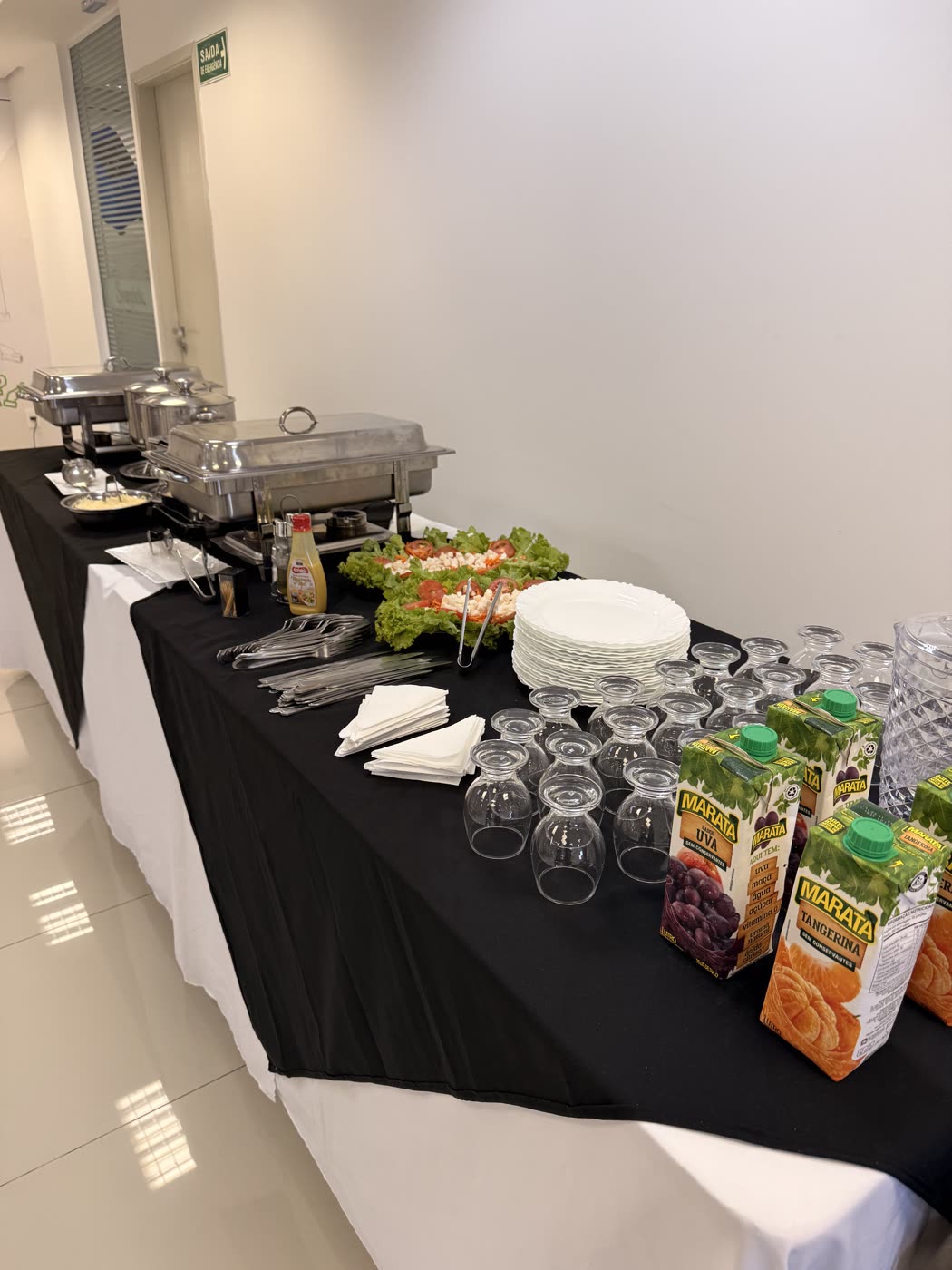 Mesa de almoço corporativo montada com pratos, talheres e bebidas em SP
